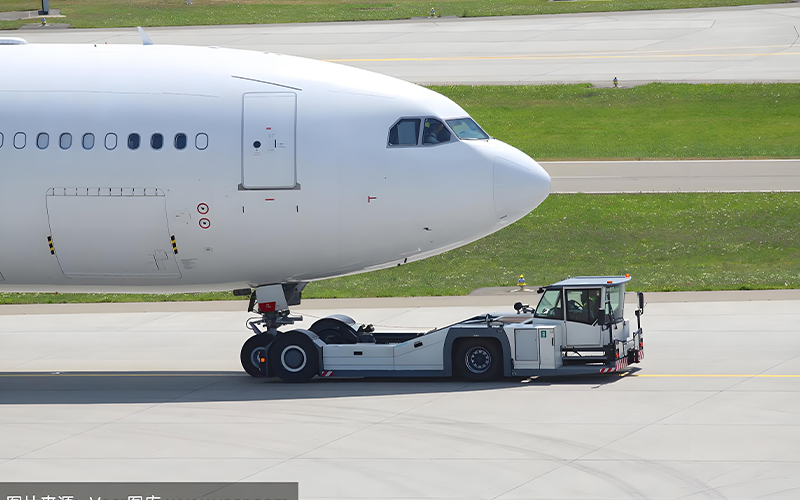 Electric aircraft tug positioned at the nose of an airplane,准备 tow it